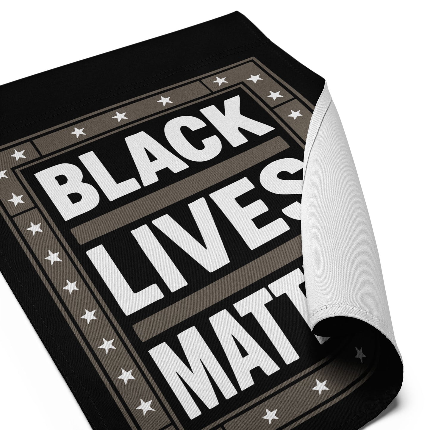 Close-up of the Black Lives Matter garden flag, showing curled fabric corner and detailed star border design.