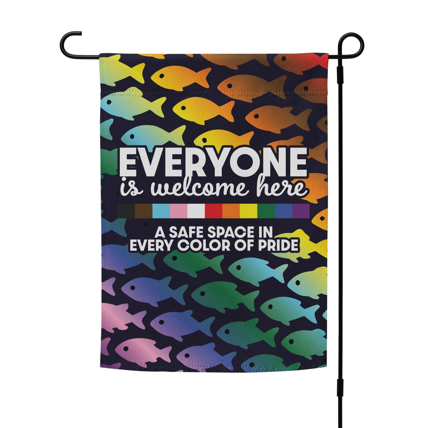 “Everyone Is Welcome Here” LGBTQ+ pride garden flag with rainbow fish design, displayed on a stand in front yard setting.