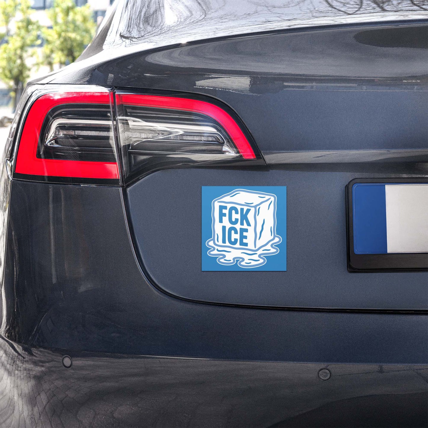 Car magnet mounted on vehicle bumper showing stylized melting ice cube graphic, flat vector design with white text on blue field, printed message “FCK ICE.”