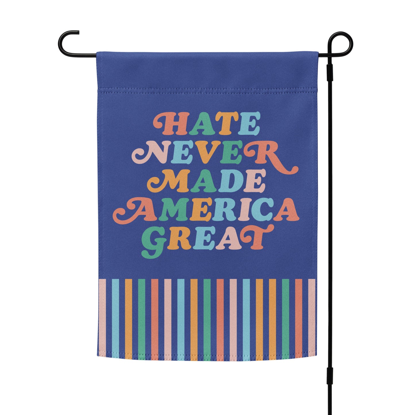 “Hate Never Made America Great” progressive garden flag on a stand, featuring rainbow retro text and colorful striped border.