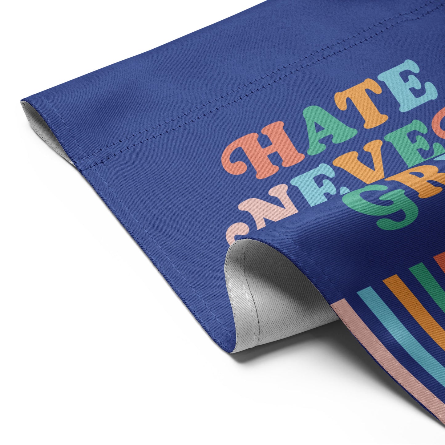 Detailed folded view of the “Hate Never Made America Great” garden flag showing bright lettering and striped pattern at the bottom.