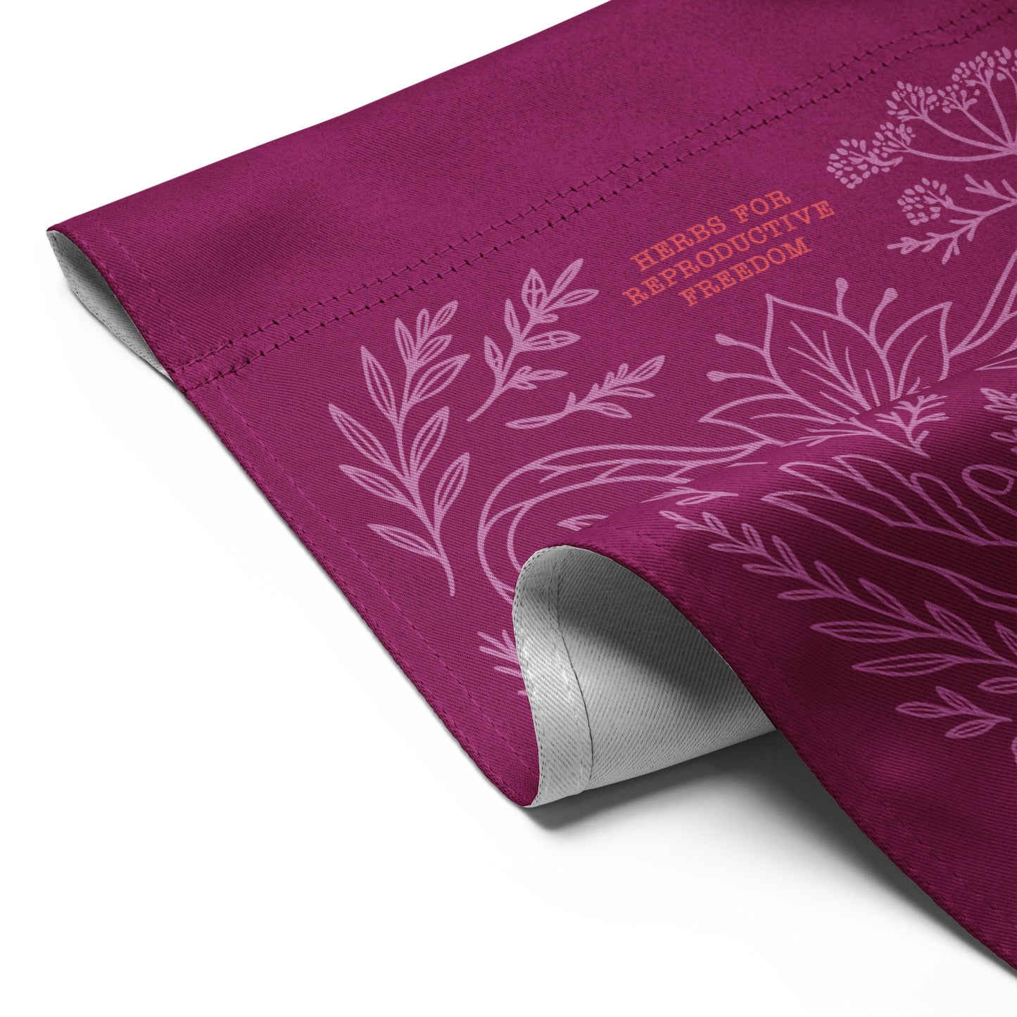 Rolled magenta flag showing fabric texture and “Herbs for Reproductive Freedom” print in light pink line art. Eco-conscious flag by Blue Wave USA.