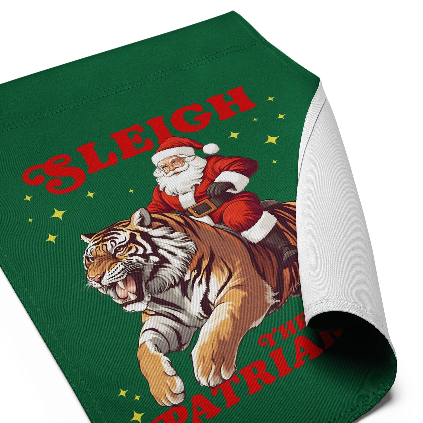 Close-up of the “Sleigh the Patriarchy” progressive holiday garden flag with curled corner showing Santa on tiger design, Blue Wave USA activist décor.