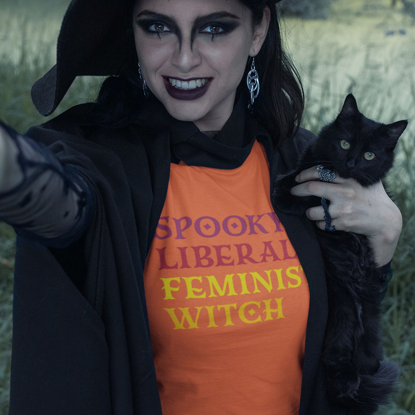 Model wearing the Spooky Liberal Feminist Witch Unisex T-Shirt with a Halloween-inspired background.