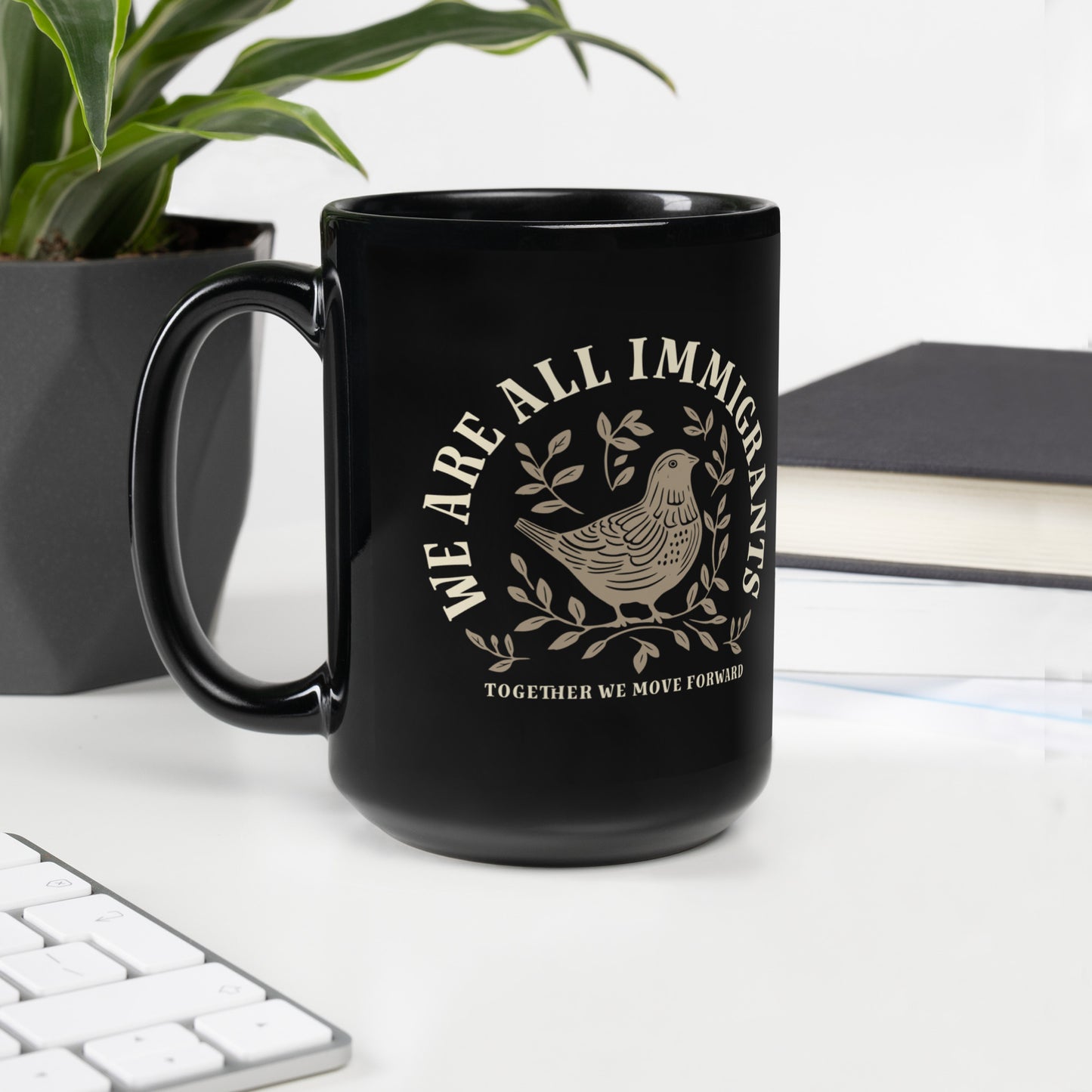 Close-up of linocut dove and leaves design with 'We Are All Immigrants' phrase on black mug.