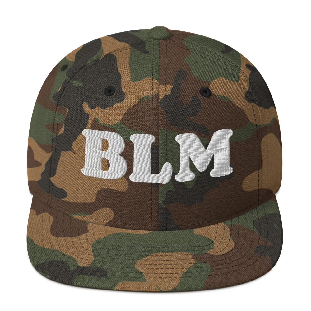 Camouflage snapback hat with raised embroidered “BLM” lettering, patterned fabric crown with flat brim and structured streetwear style.