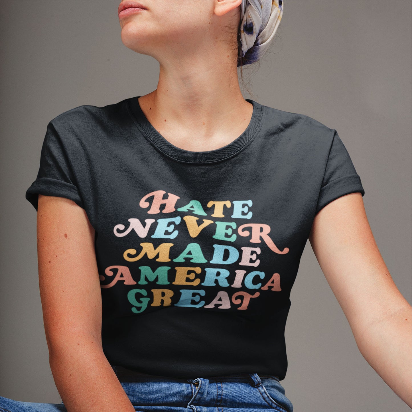 Model wearing the “Hate Never Made America Great” black t-shirt with retro rainbow text.