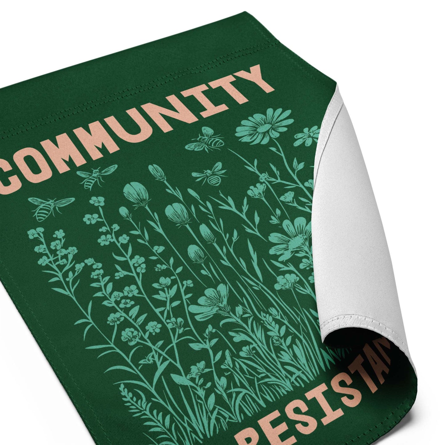 Tight crop of the word “COMMUNITY” printed in cream block letters above fine line botanical illustrations, showing the quality of the print and the message’s quiet strength.
