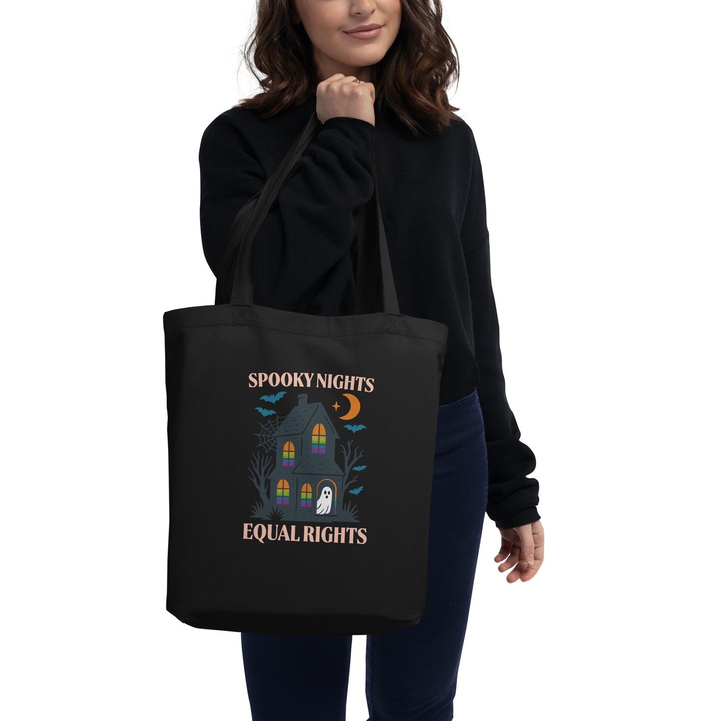 Model carrying “Spooky Nights, Equal Rights” eco tote with haunted house artwork, Blue Wave USA progressive apparel accessory for spooky season.