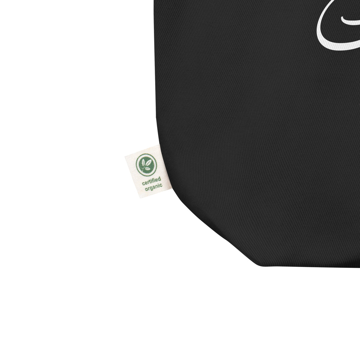 Close-up of the black eco tote bag showing the fabric, reinforced corner, and product label beside the “Protect Trans Kids” design.