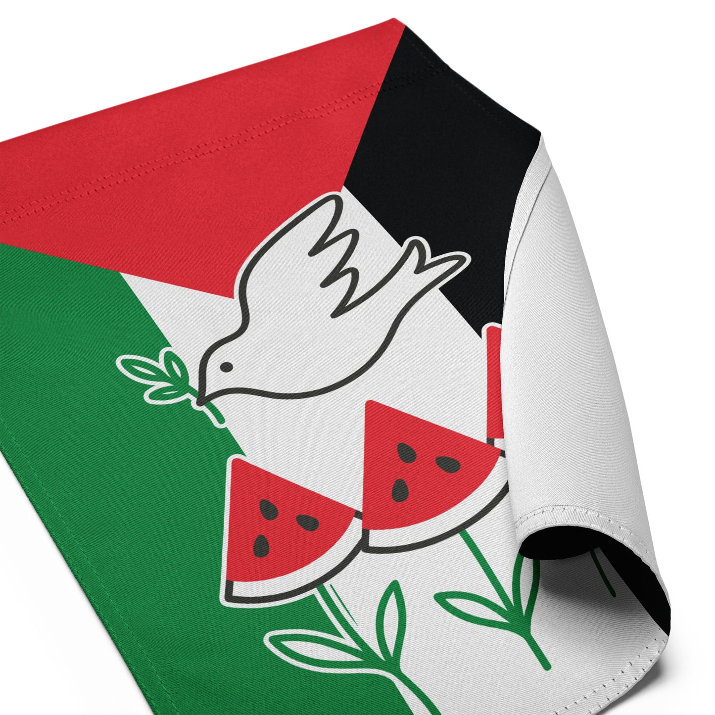 Close-up angled view of the Free Palestine activist garden flag with curled fabric corner, showing dove and watermelon detail, Blue Wave USA activist décor.