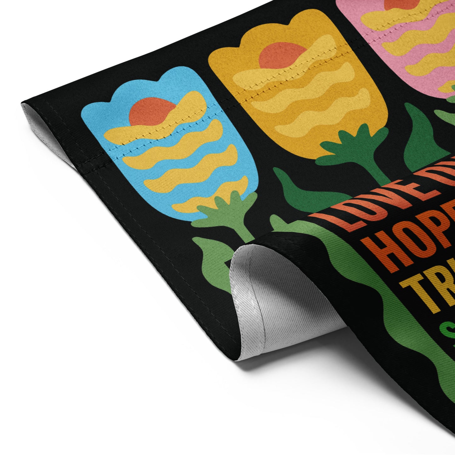 Detailed view of the “In This House We Believe” progressive garden flag with tulip illustration and message against black background.