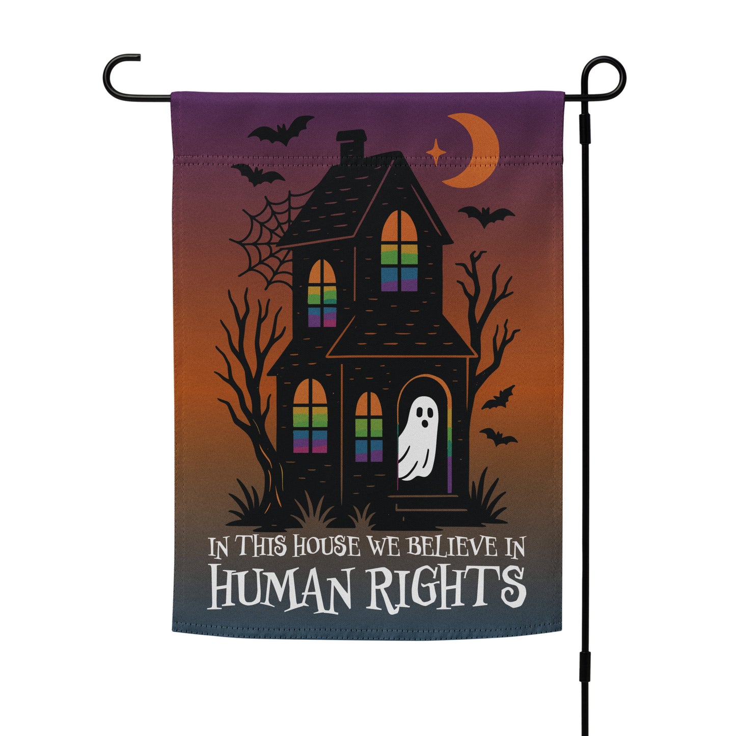 “In This House We Believe in Human Rights” progressive Halloween garden flag with haunted house design, displayed outdoors, Blue Wave USA activist décor.
