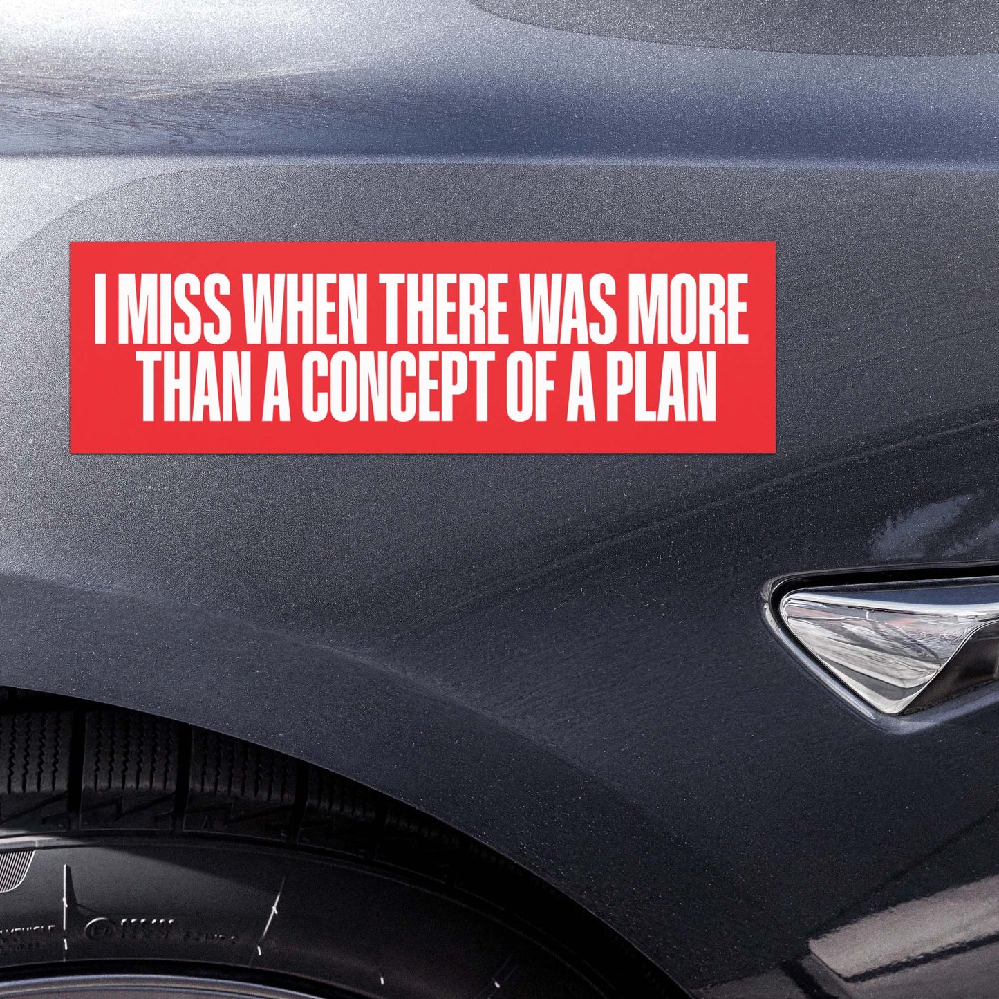 Car magnet displayed on vehicle bumper with bold white text reading “I MISS WHEN THERE WAS MORE THAN A CONCEPT OF A PLAN” on red background.