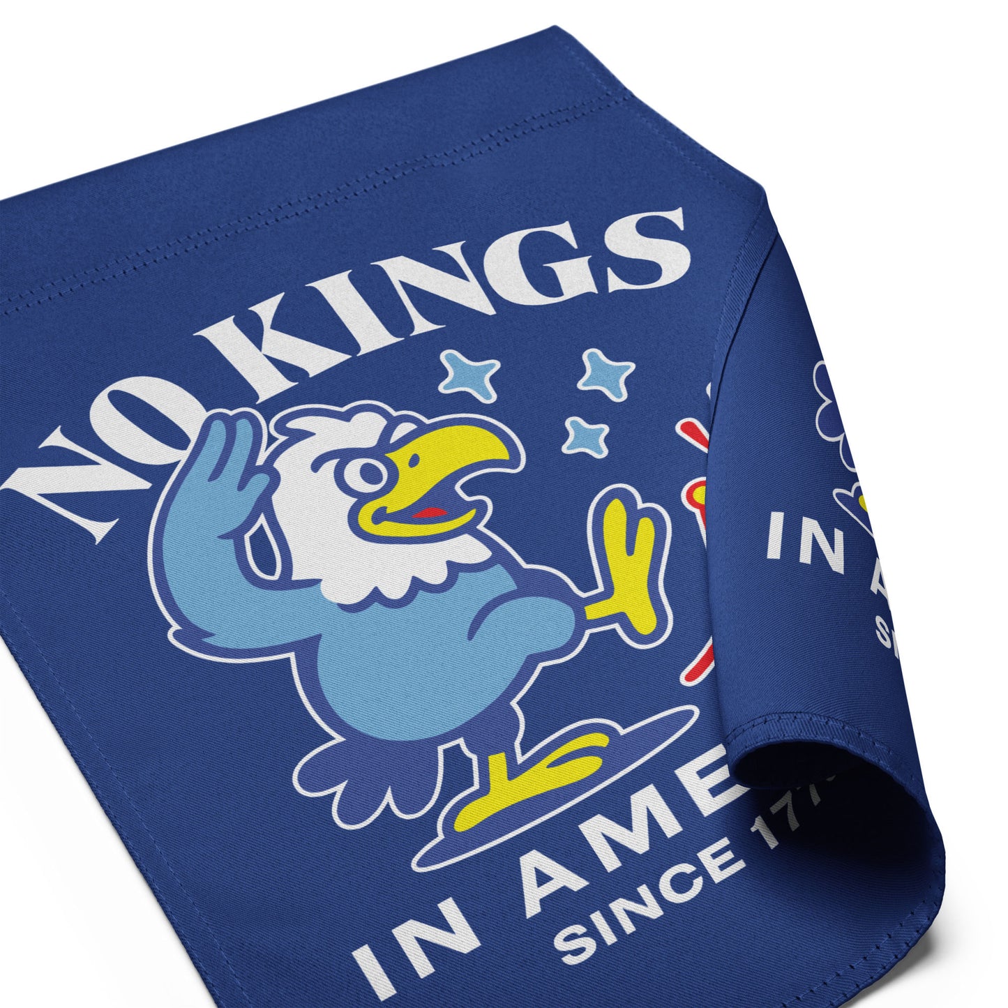 Angled view of garden flag showing folded fabric with eagle artwork and partial “NO KINGS IN AMERICA SINCE 1776” slogan.