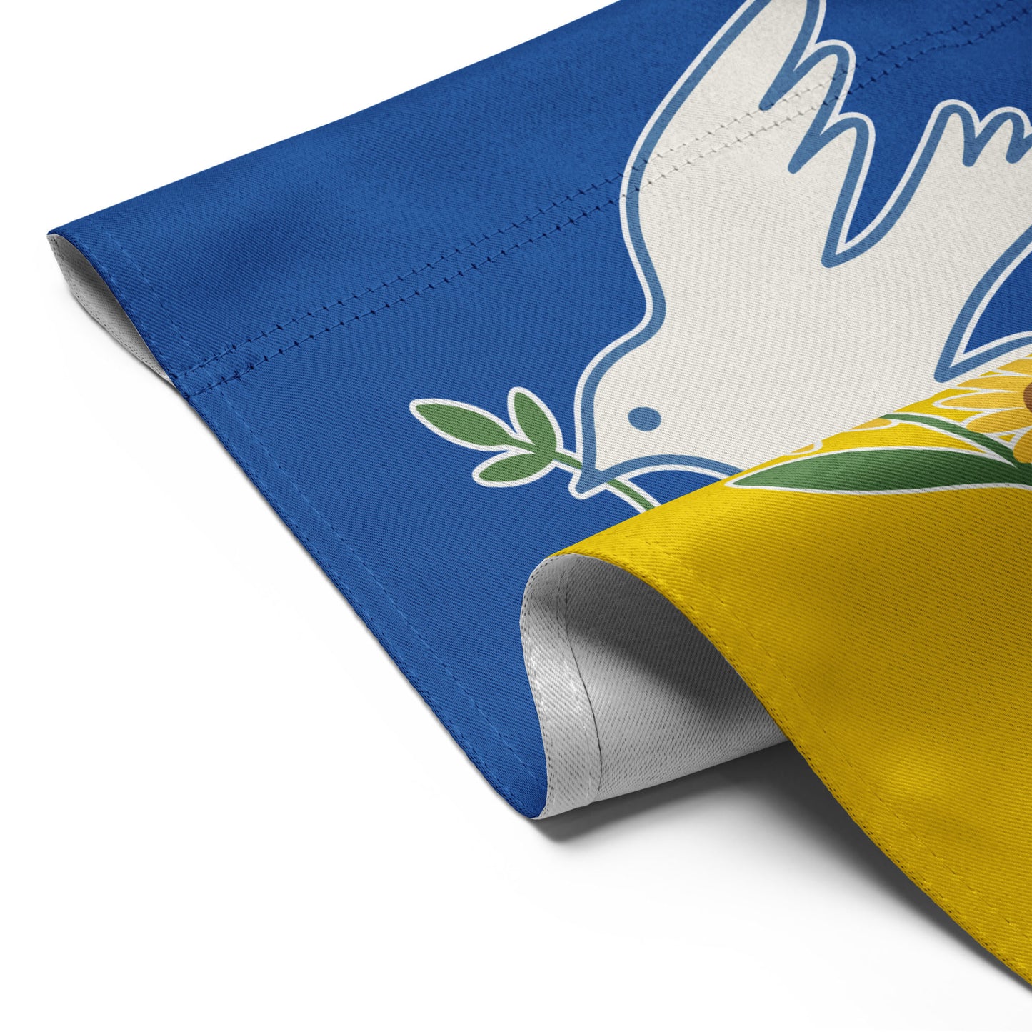 Detailed corner view of the “Peace for Ukraine” garden flag showing stitched edge and part of dove and sunflower artwork.