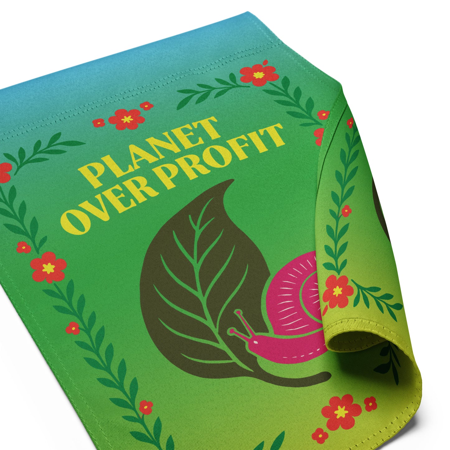 Close-up of the “Planet Over Profit” environmental garden flag with curled corner showing snail and floral details, Blue Wave USA progressive décor
