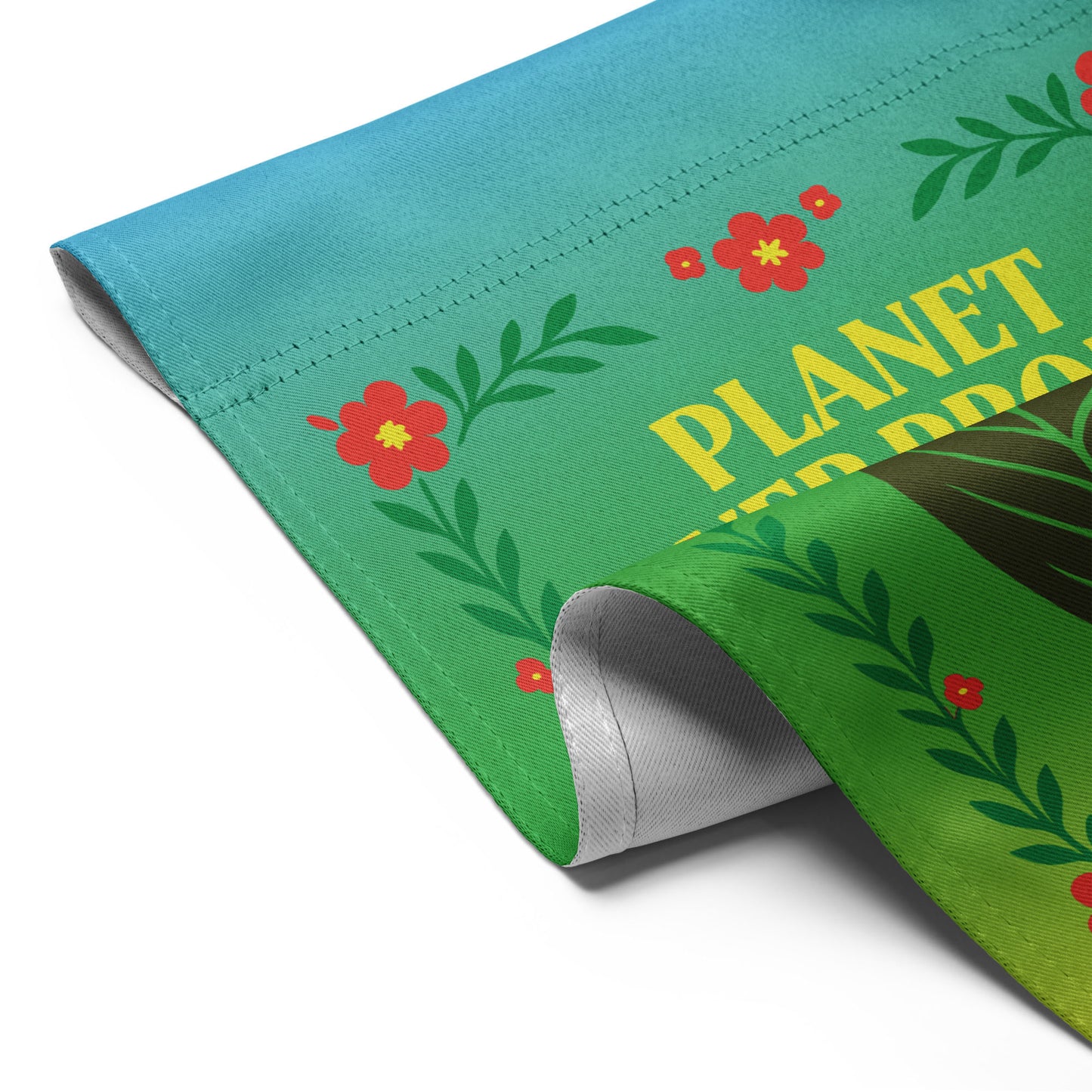 Angled view of the “Planet Over Profit” garden flag showing folded corner with floral border and leaf design.