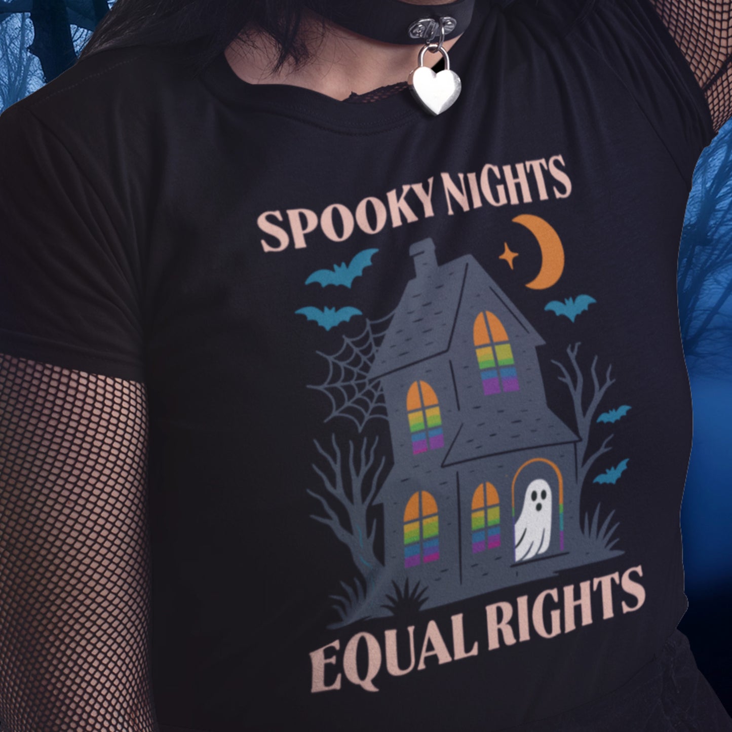Model wearing the “Spooky Nights Equal Rights” Halloween activist t-shirt with haunted house, ghost, bats, crescent moon, and rainbow Pride windows, sold by Blue Wave USA progressive apparel.
