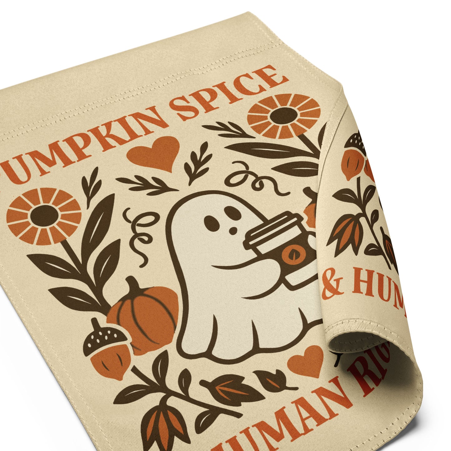 Close-up angled view of the “Pumpkin Spice & Human Rights” garden flag with curled fabric edge showing ghost, pumpkins, and floral artwork.