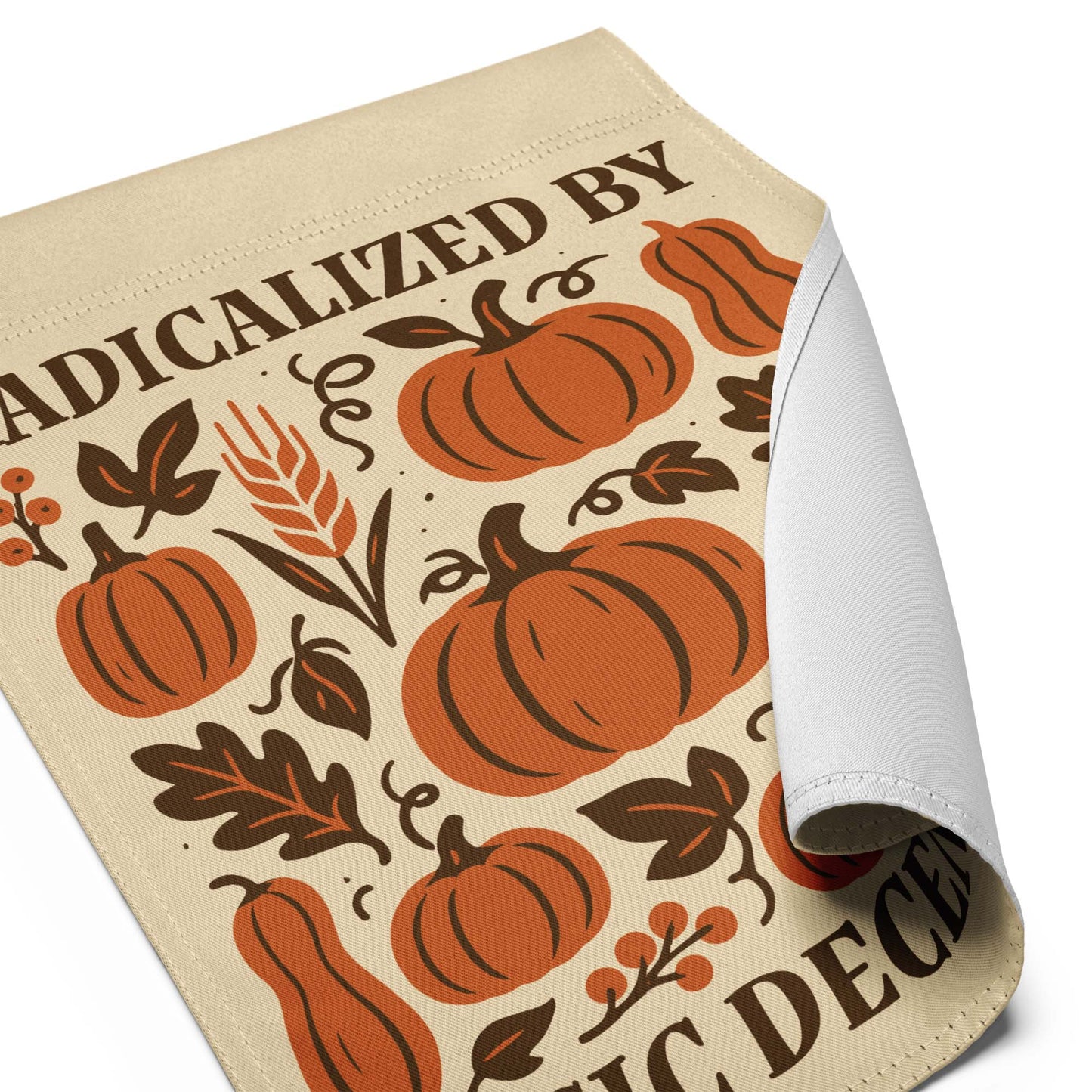 Close-up of the “Radicalized By Basic Decency” Thanksgiving garden flag with curled edge showing pumpkin and leaf artwork.