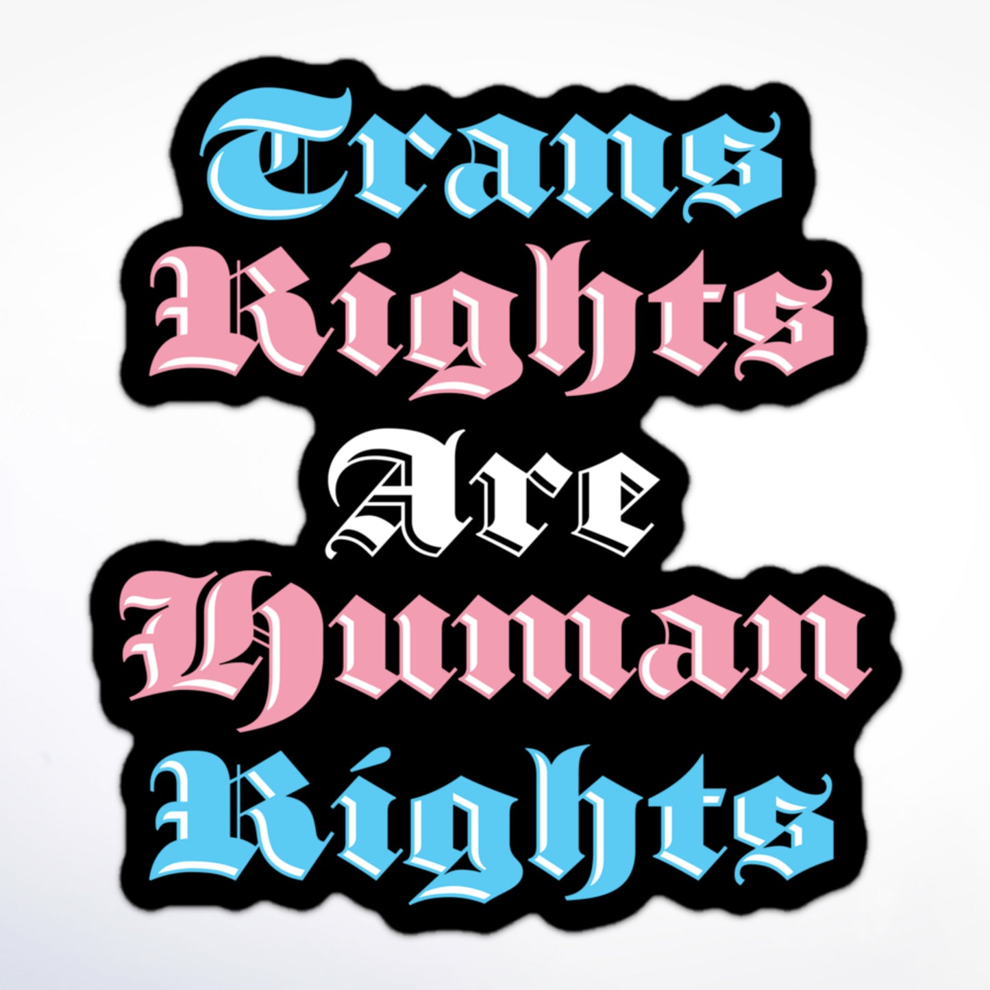 Sticker with bold gothic lettering in pink, blue, and white that says “Trans Rights Are Human Rights” on a black outline.