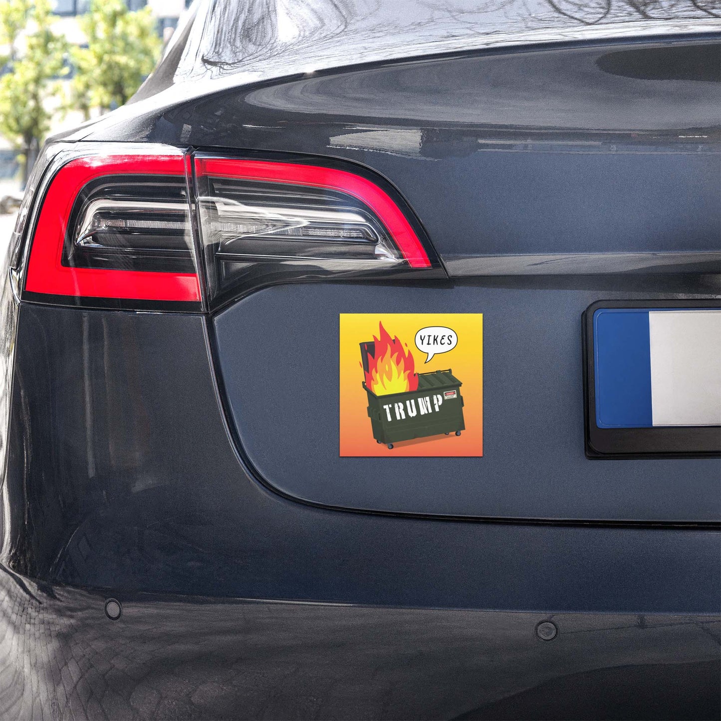 Car magnet displayed on rear of vehicle showing flaming dumpster illustration with “TRUMP” text and “YIKES” speech bubble, anti-Trump design from Blue Wave USA.