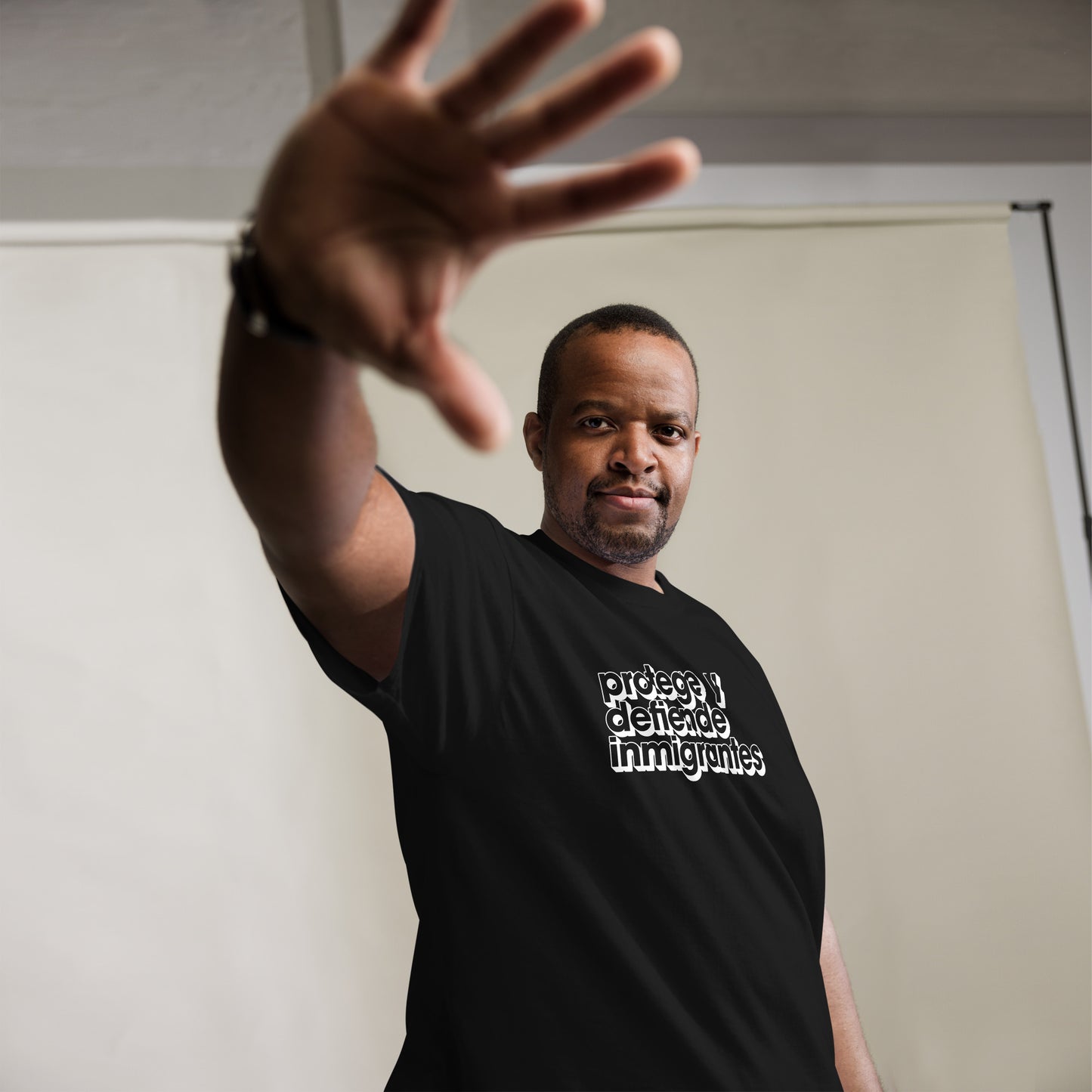 Lifestyle Image: Black Model wearing Protege y Defiende Inmigrantes pro-migrant rights unisex shirt