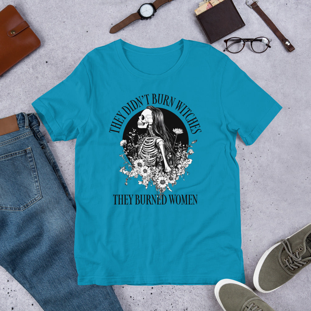 Flat lay of t-shirt with bold feminist text and intricate skeleton girl floral design.