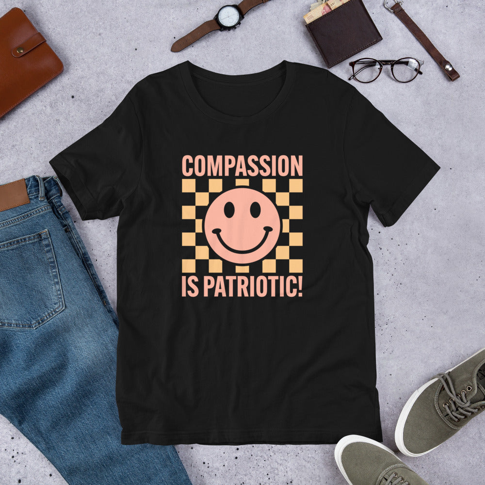 Flat lay of the Compassion Is Patriotic Smiley Face T-Shirt with a clean background and accessories.