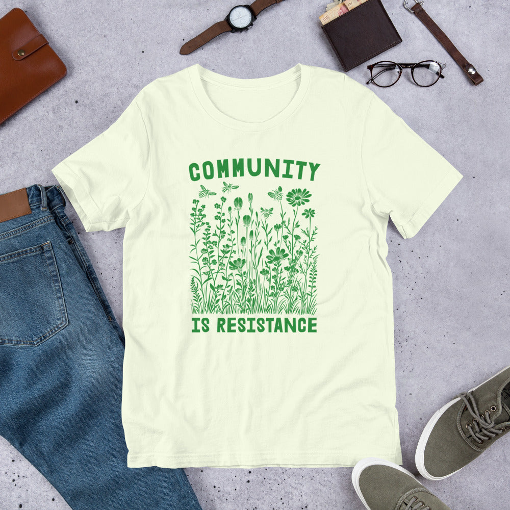 Flat Lay Image with accessories: Community Is Resistance T-Shirt spread flat to highlight the message.