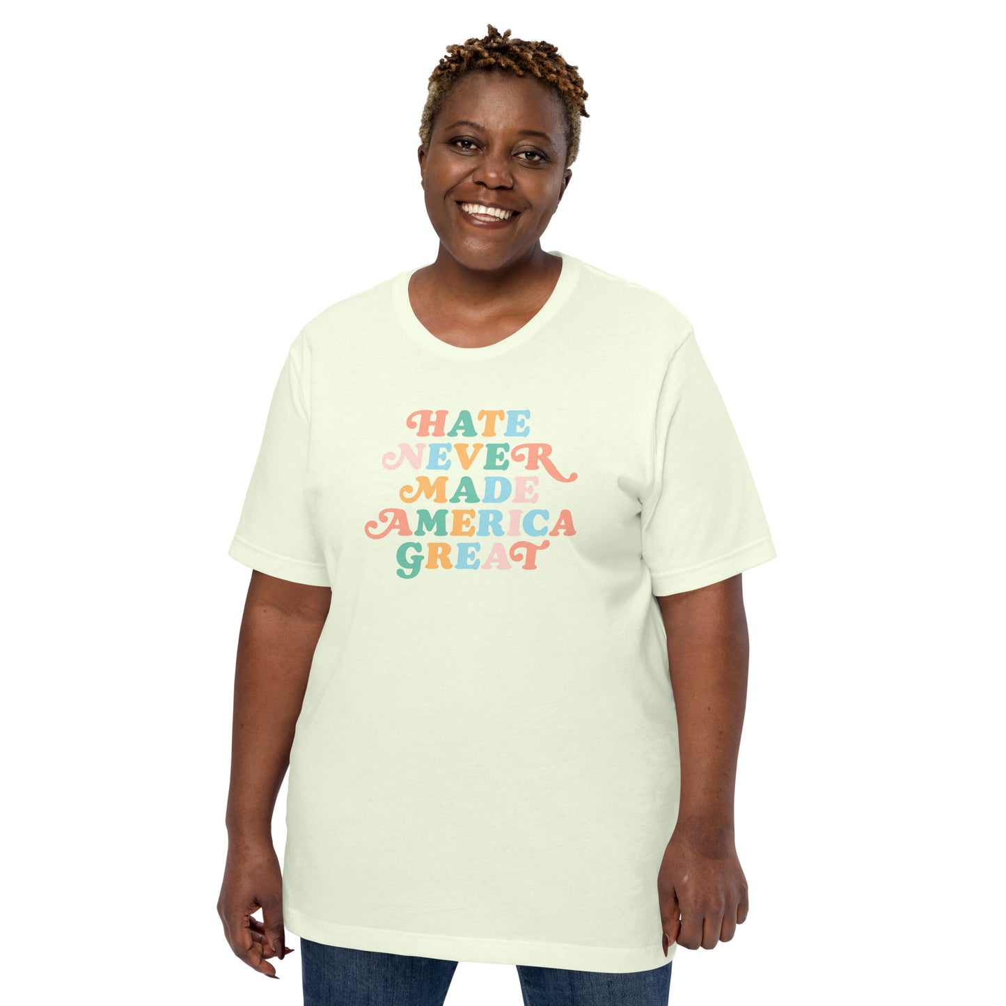 Model wearing light-colored “Hate Never Made America Great” t-shirt with bold rainbow retro lettering.