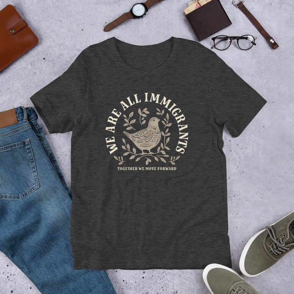 Flat lay of We Are All Immigrants T-Shirt featuring linocut dove and leaves design.