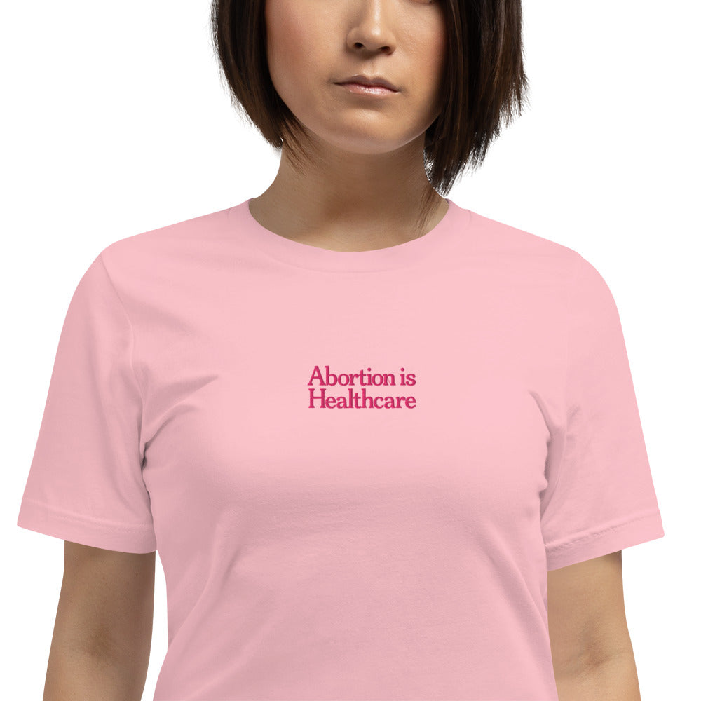 Woman wearing the"Abortion Is Healthcare" Reproductive Rights Embroidered Unisex T-Shirt
