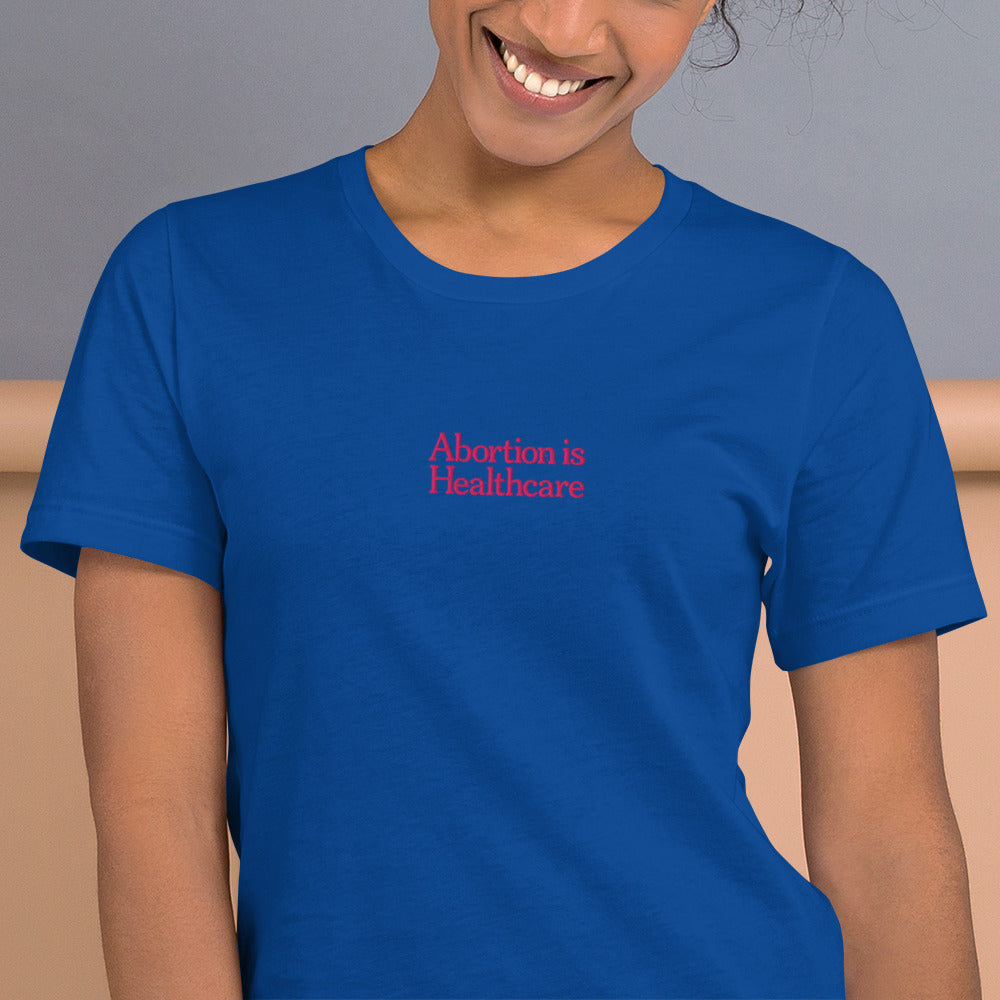 Woman wearing the"Abortion Is Healthcare" Reproductive Rights Pro Roe Embroidered Unisex T-Shirt