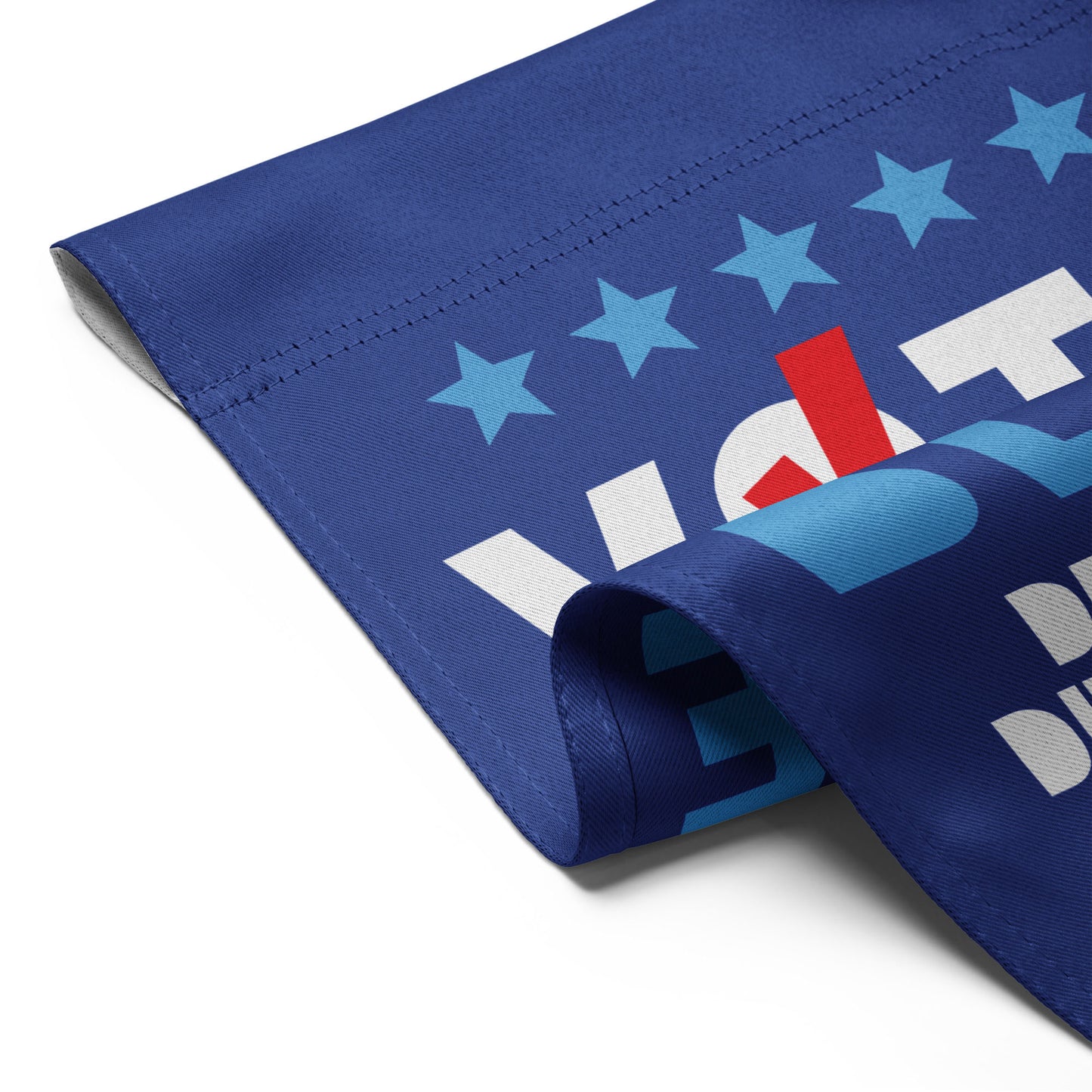 Detailed view of the garden flag folded over to show the durable stitching and the double-sided print quality of the "Vote Blue" design.