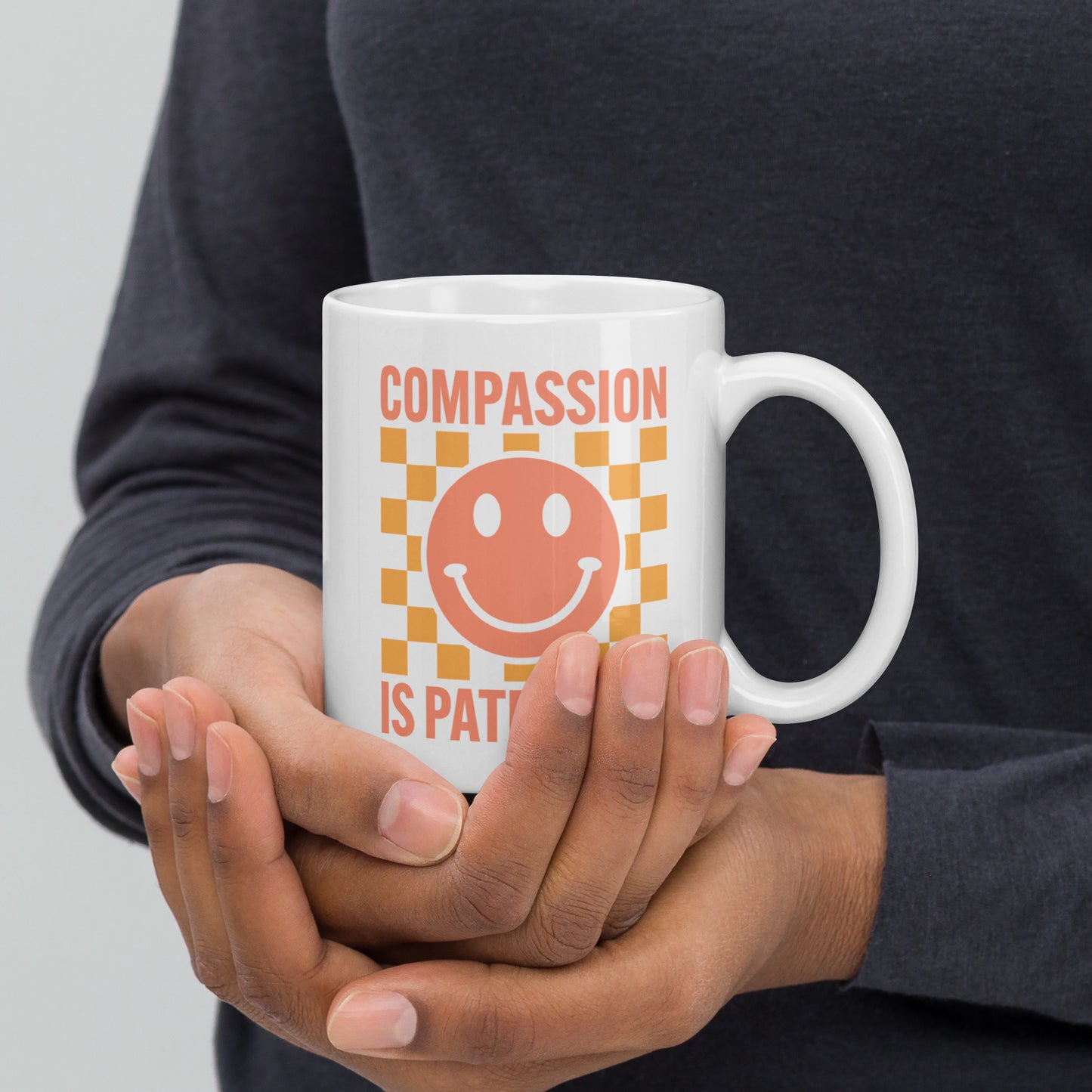 Front view of the 11 oz Compassion Is Patriotic Smiley Face White Mug featuring a cheerful smiley and bold message.