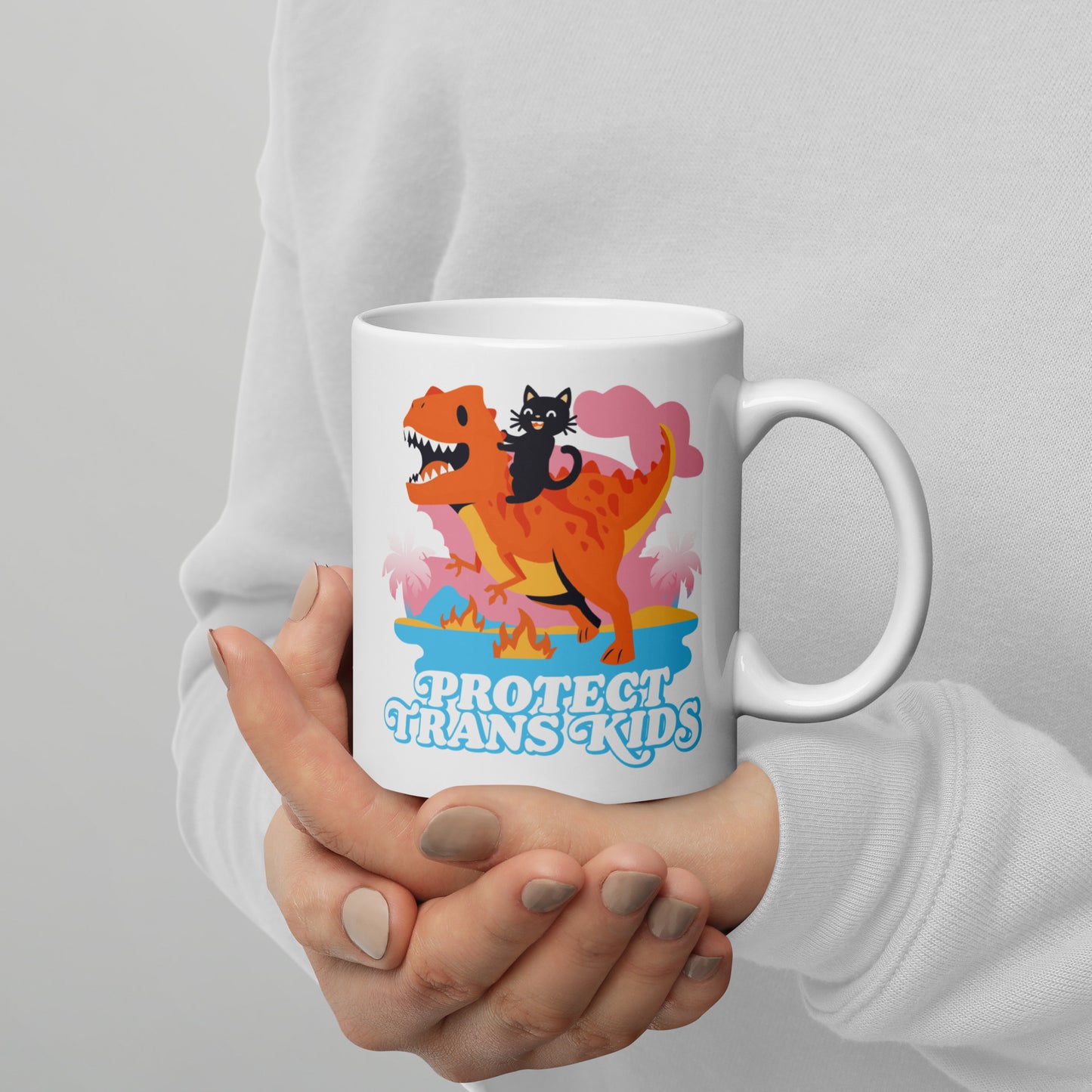 Person holding 11 oz Protect Trans Kids Mug while enjoying a hot beverage.