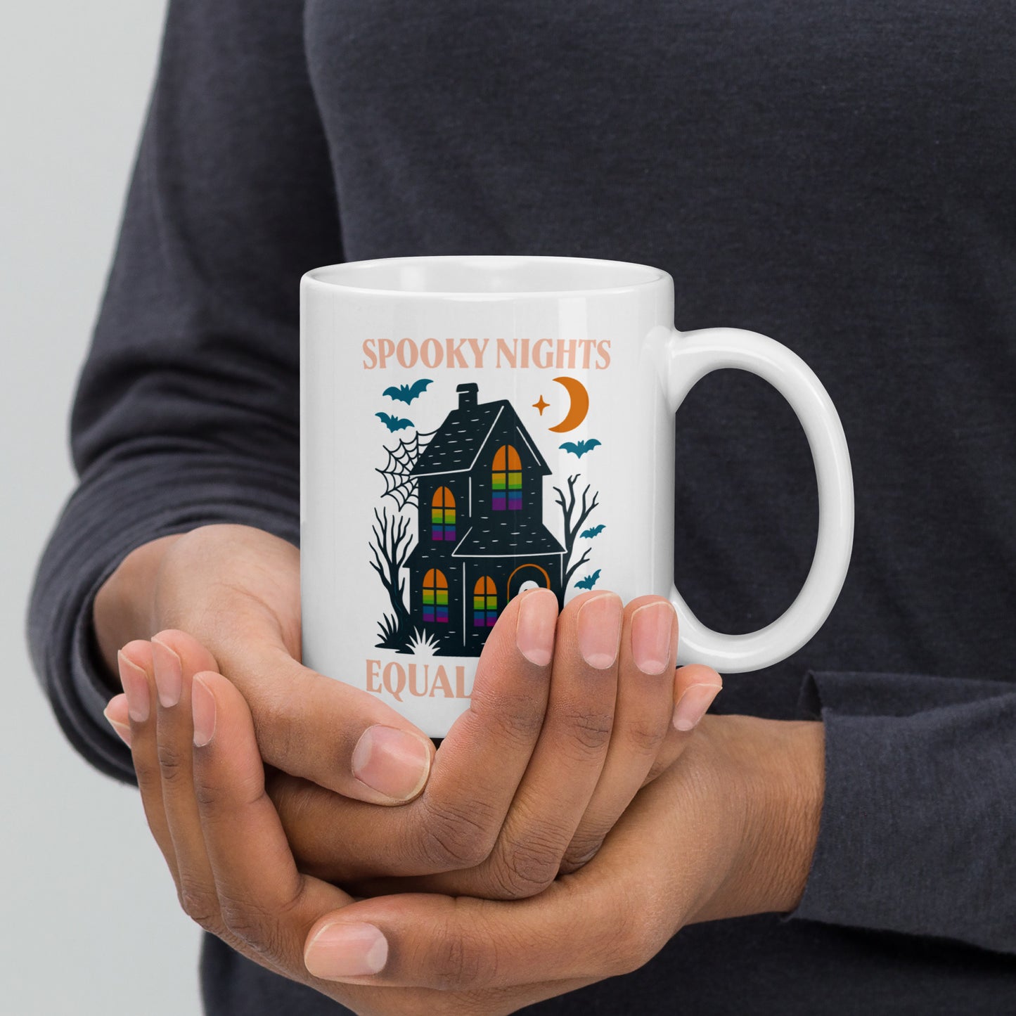 Person holding 11 oz “Spooky Nights, Equal Rights” Halloween mug with rainbow-window haunted house, Blue Wave USA progressive drinkware for spooky season.