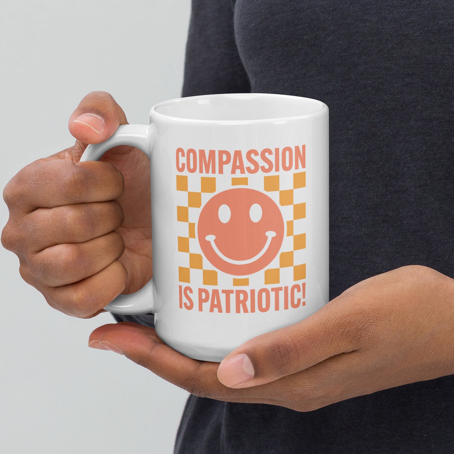 Front view of the 15 oz Compassion Is Patriotic Smiley Face White Mug featuring a cheerful smiley and bold message.