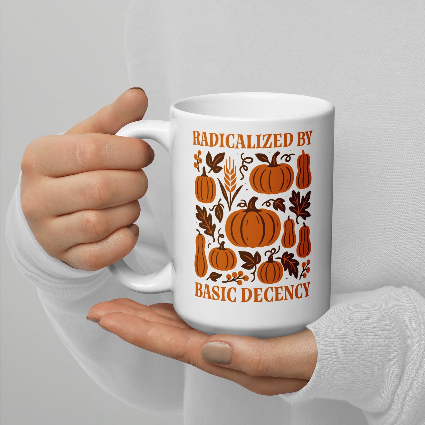 Activist mug with orange pumpkin pattern and “Radicalized by Basic Decency” message, autumn equality design for kind voters.