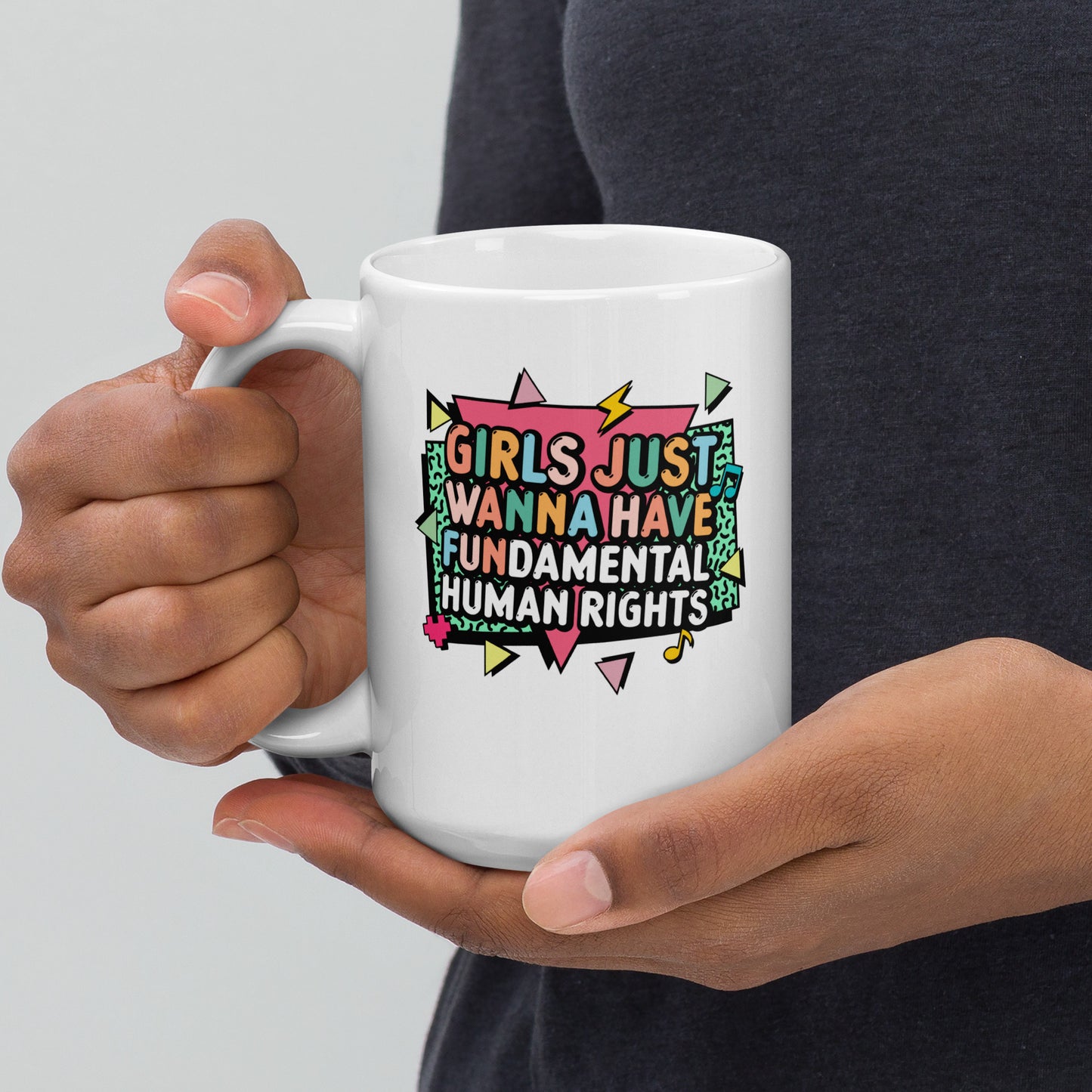 Angled view of the 15 oz “Girls Just Wanna Have Fundamental Human Rights” mug being held by one hand, showing the vibrant 80s-inspired typography and color palette. Feminist empowerment mug by Blue Wave USA.