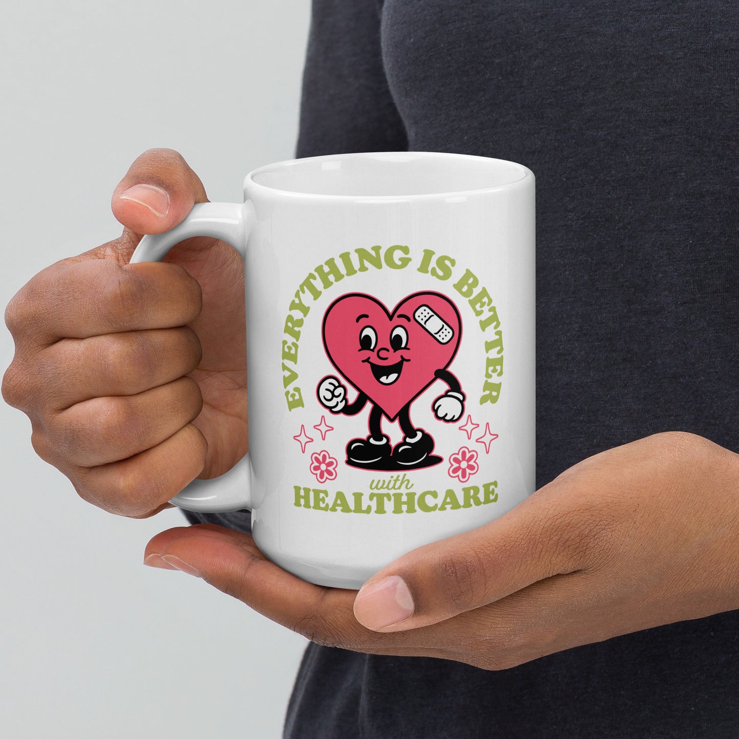 15 oz white ceramic mug with the “Everything Is Better with Healthcare” design being held up, showing full view of the heart graphic and healthcare message.