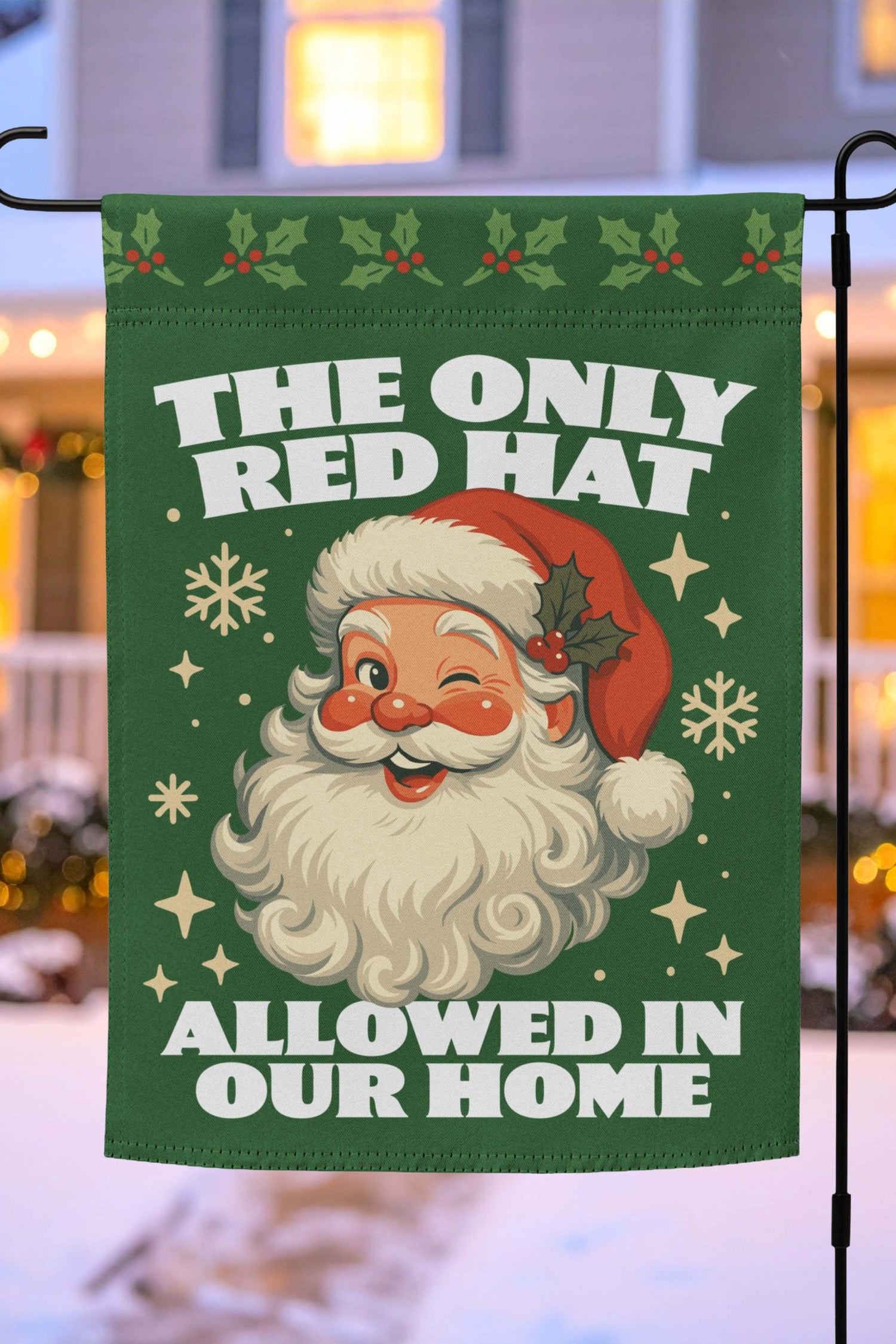 Green garden flag on a metal stand with a retro Santa illustration, holiday motifs, and the printed message “THE ONLY RED HAT ALLOWED IN OUR HOME,” outdoor décor .