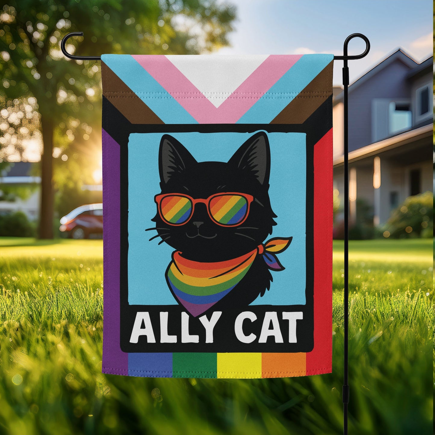 “Ally Cat” LGBTQ+ pride garden flag featuring a black cat with rainbow sunglasses and scarf on a progress pride flag background, displayed outdoors on a flagpole.