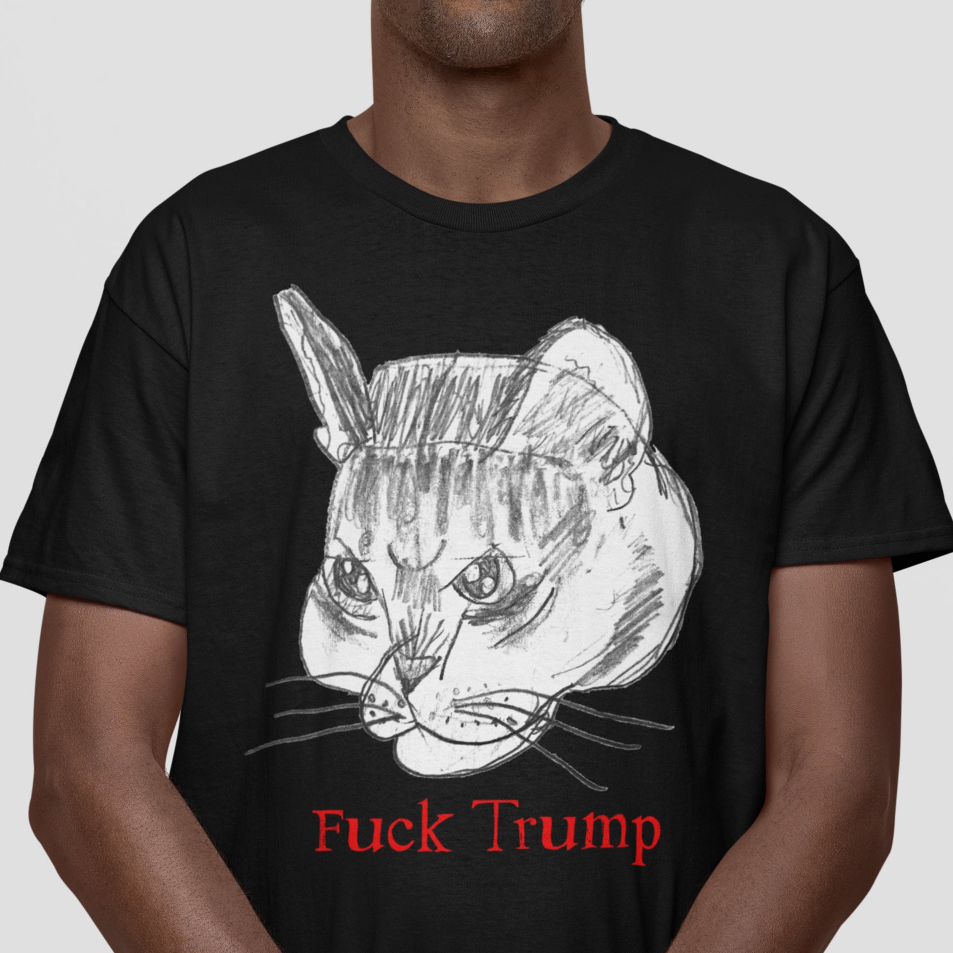 Model wearing black unisex t-shirt with sketched cat face illustration and red text reading “Fuck Trump,” casual studio lighting.