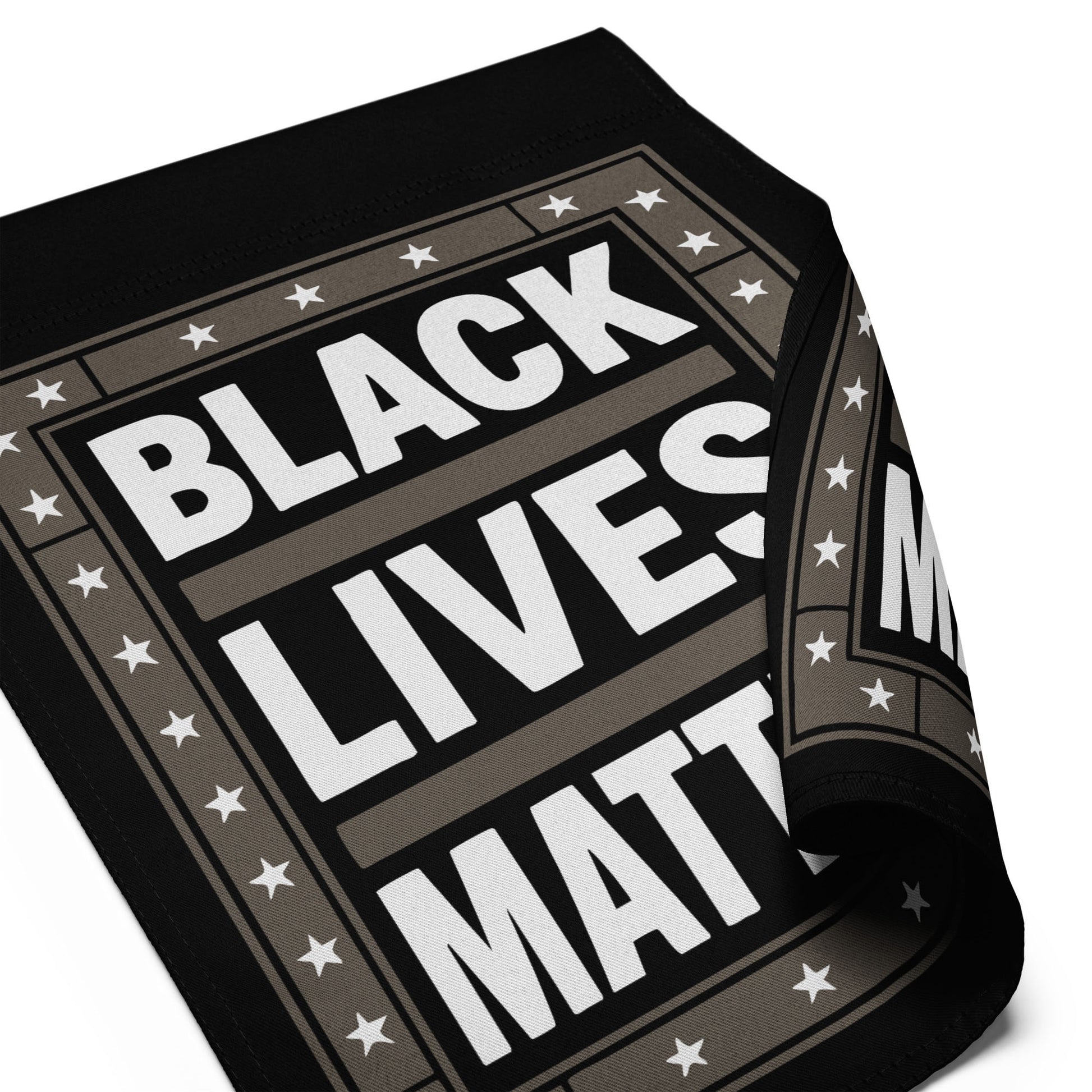 Close-up of the Black Lives Matter garden flag, showing curled fabric corner and detailed star border design.