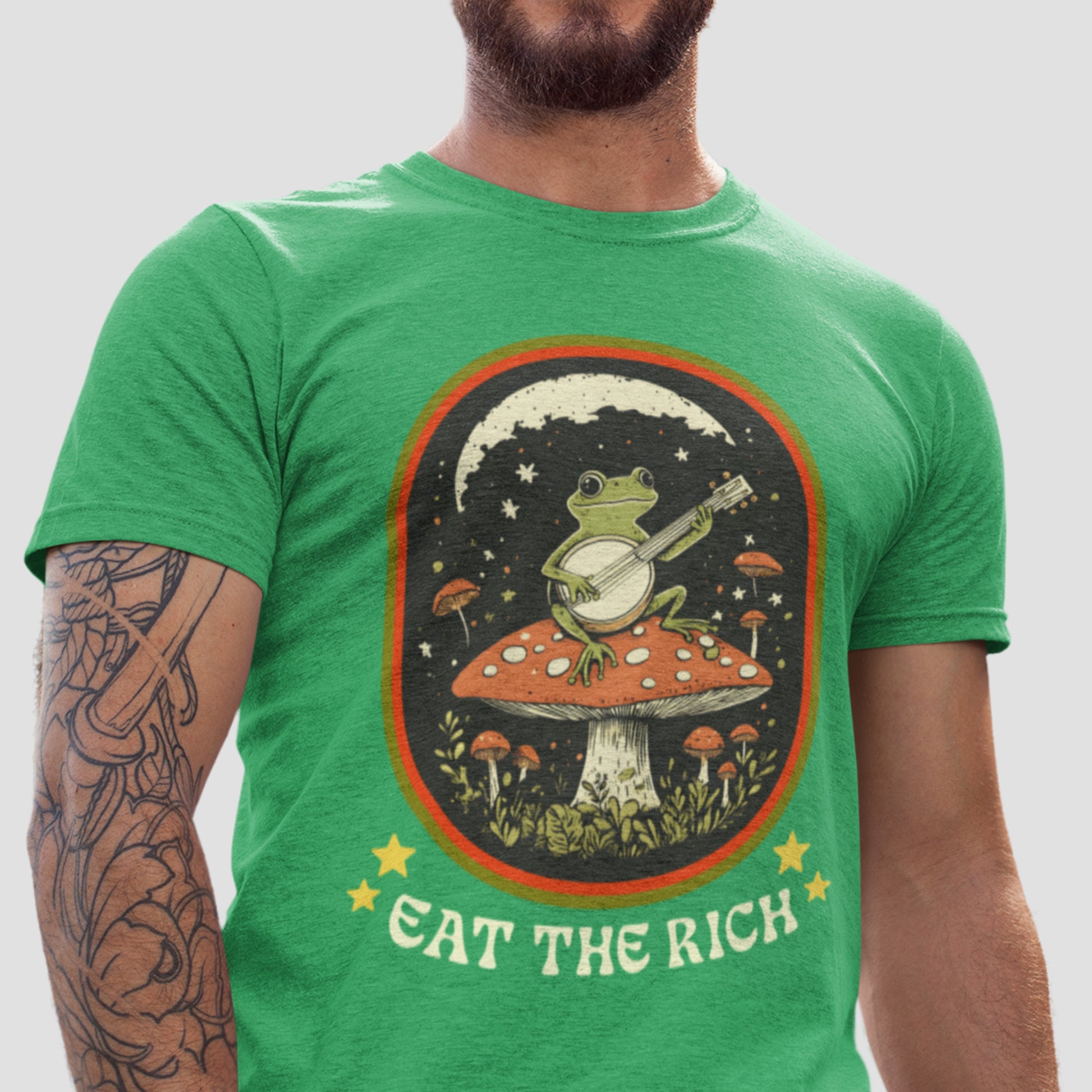 Model wearing heather kelly green unisex t-shirt featuring frog playing banjo on mushroom illustration, anti-capitalism graphic apparel from Blue Wave USA.