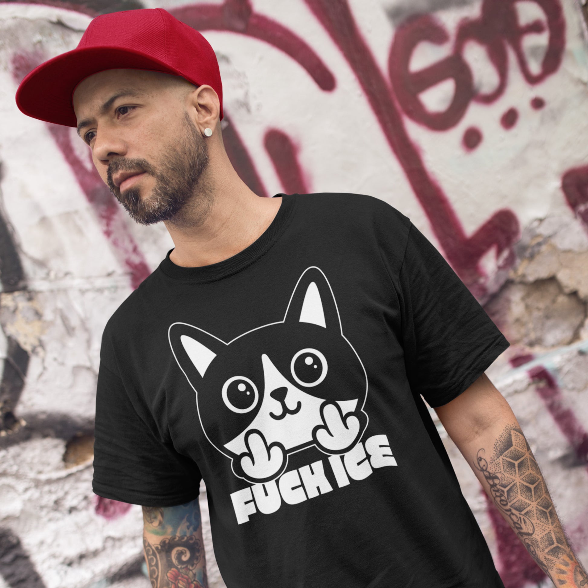 Model wearing black t-shirt with bold graphic cat illustration giving the middle finger, high-contrast white print, centered design, printed message “FUCK ICE,” outdoor urban setting.