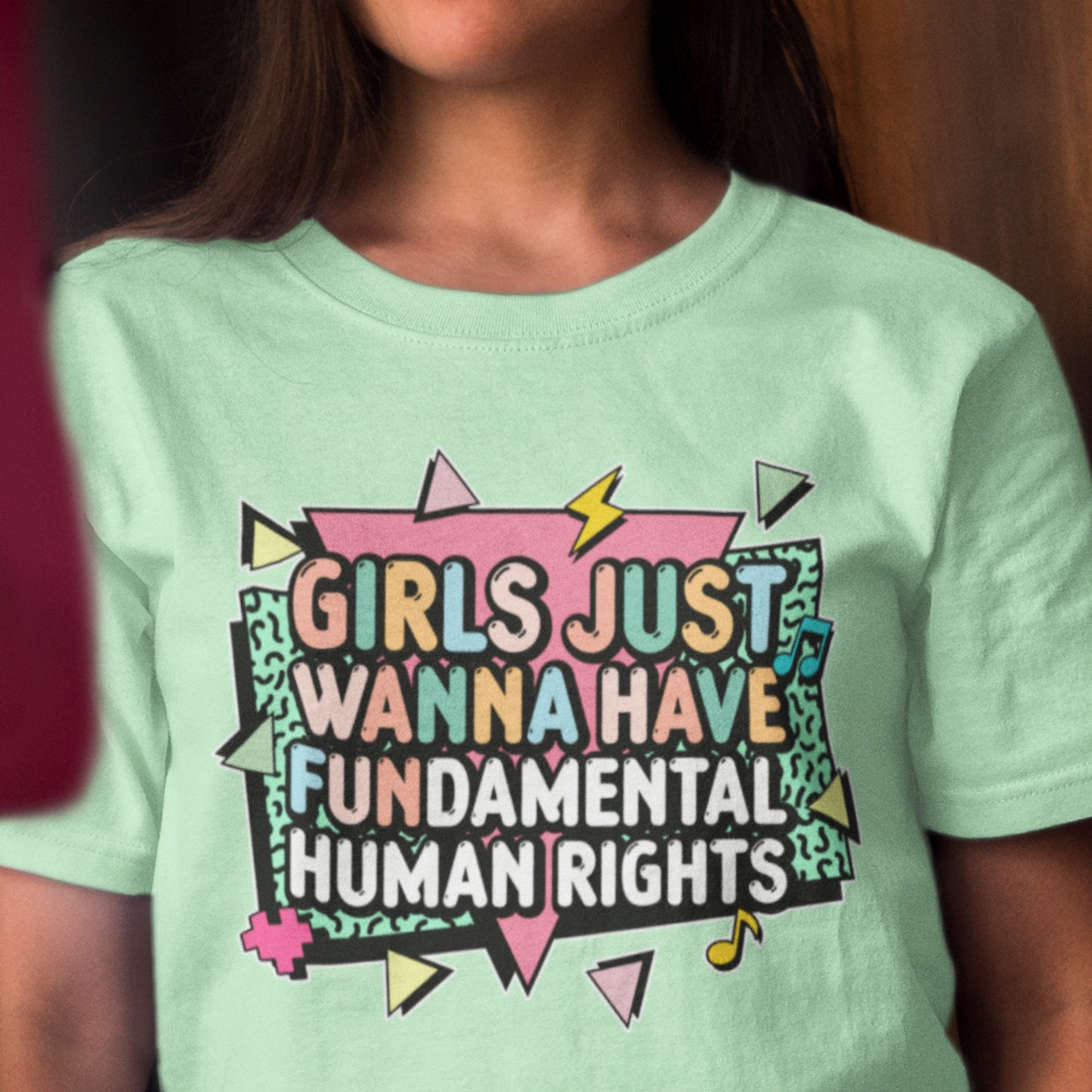 Model wearing mint green “Girls Just Wanna Have Fundamental Human Rights” feminist t-shirt with colorful retro design. Retro feminist tee by Blue Wave USA.